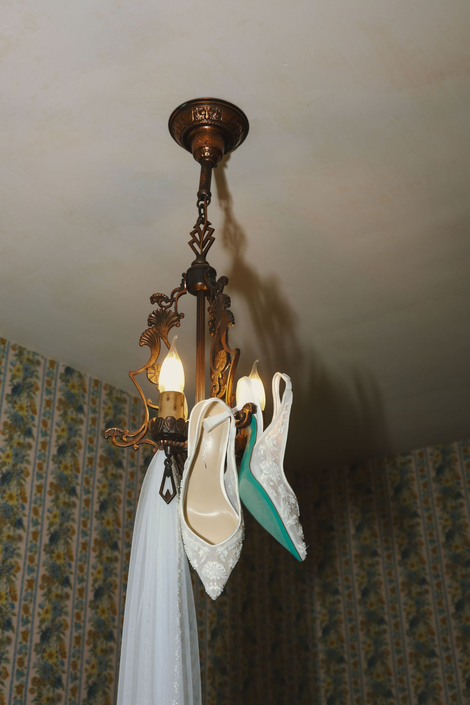 Antique brass ceiling light fixture with retro floral pattern wallpaper visible in dim lighting.