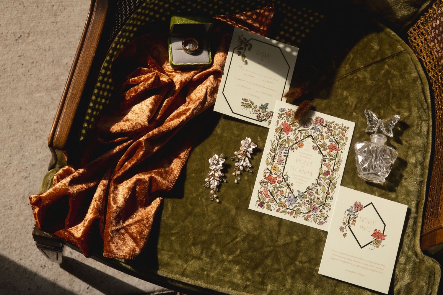 Overhead view of copper velvet fabric and vintage-style cards arranged on a dark green velvet background.