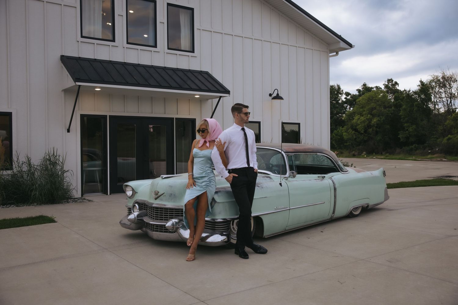 A mint green classic Cadillac convertible parked in front of a modern white building.