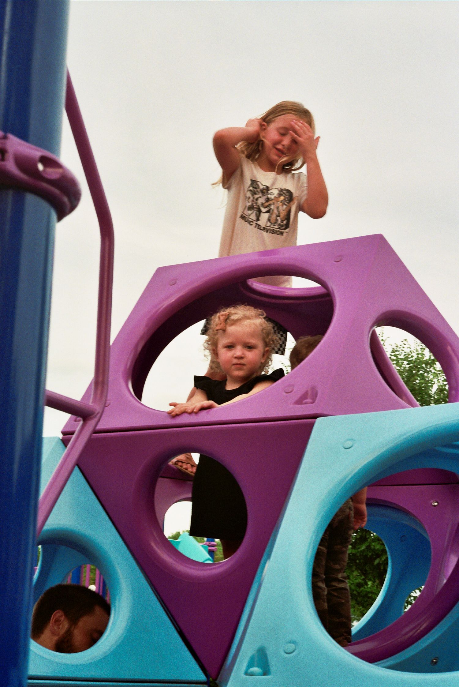 Sequence of playground photos showing children peeking through colorful purple and blue climbing equipment holes.