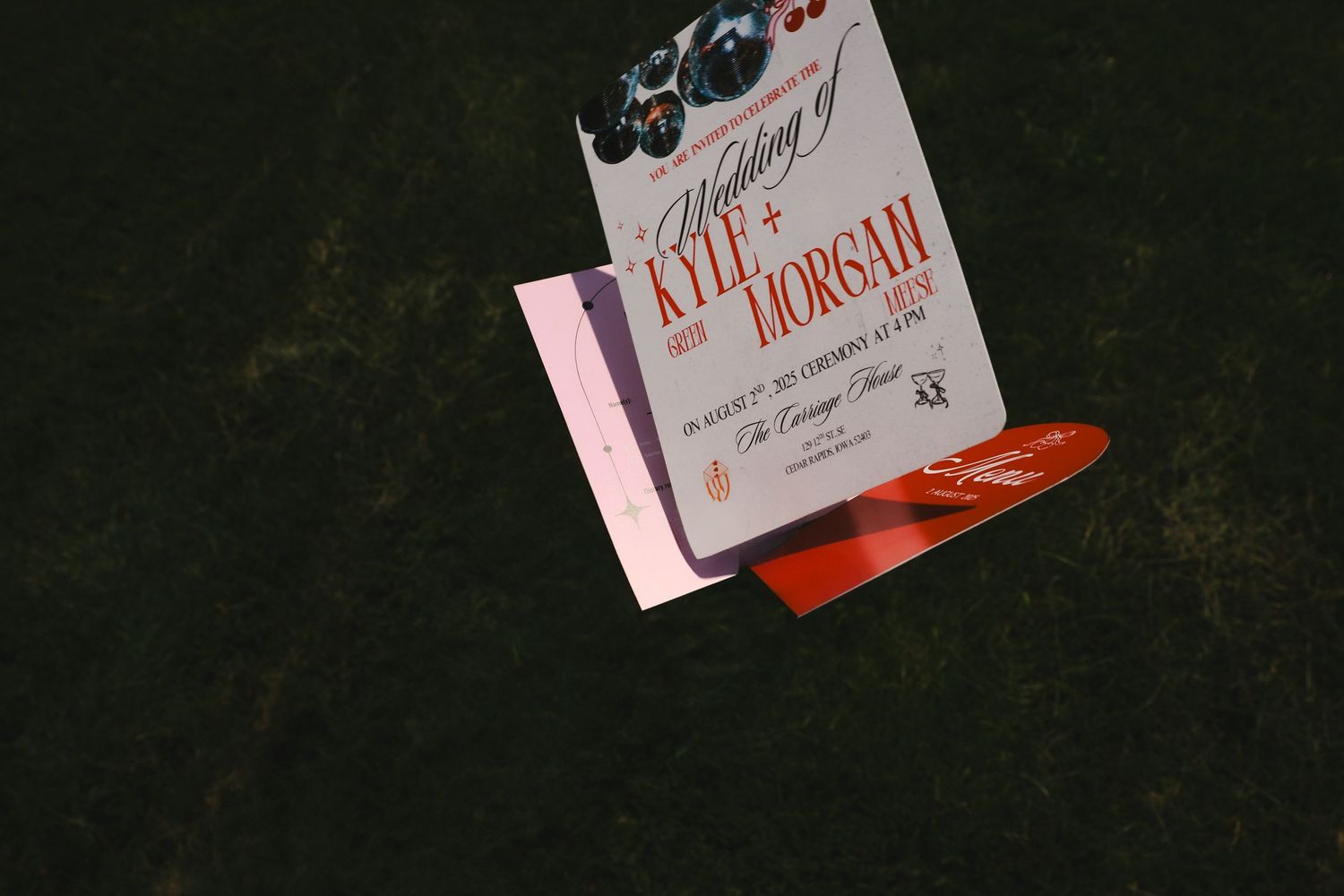 A small white book on a dark surface with a red pen lying beside it.
