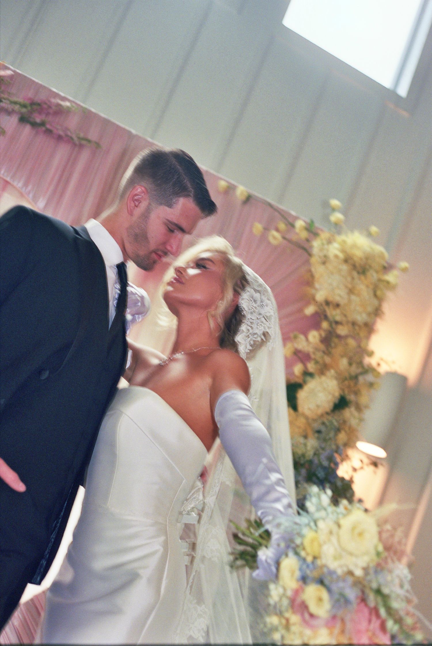 A bride and groom share passionate kisses in a sequence of romantic wedding photos with floral decorations in the background.