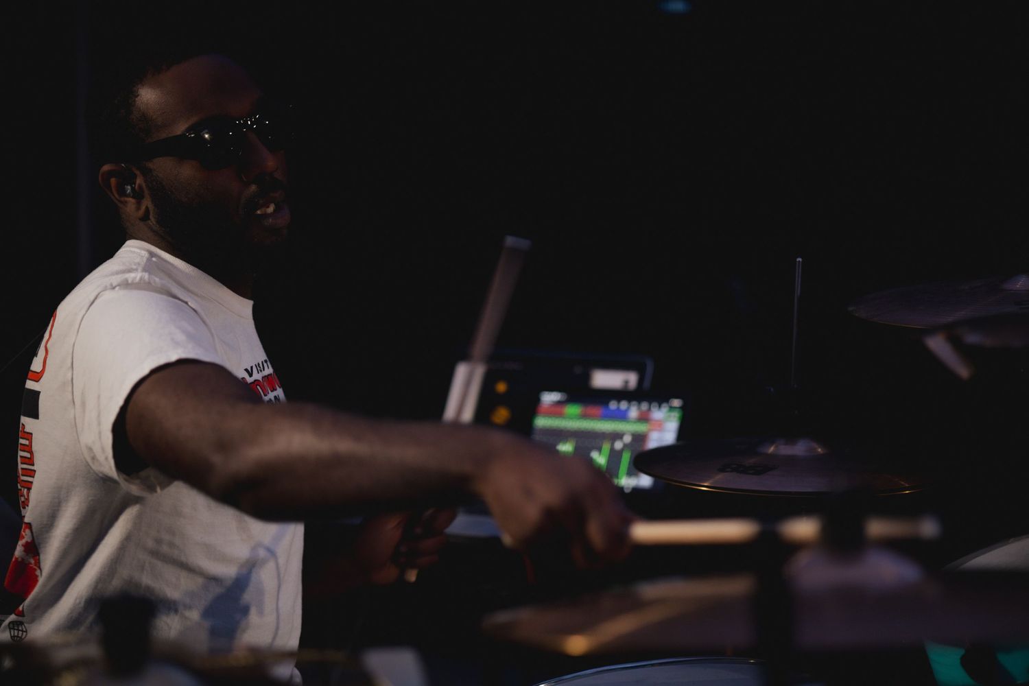 DJ performs behind equipment on dark stage at nightclub event.