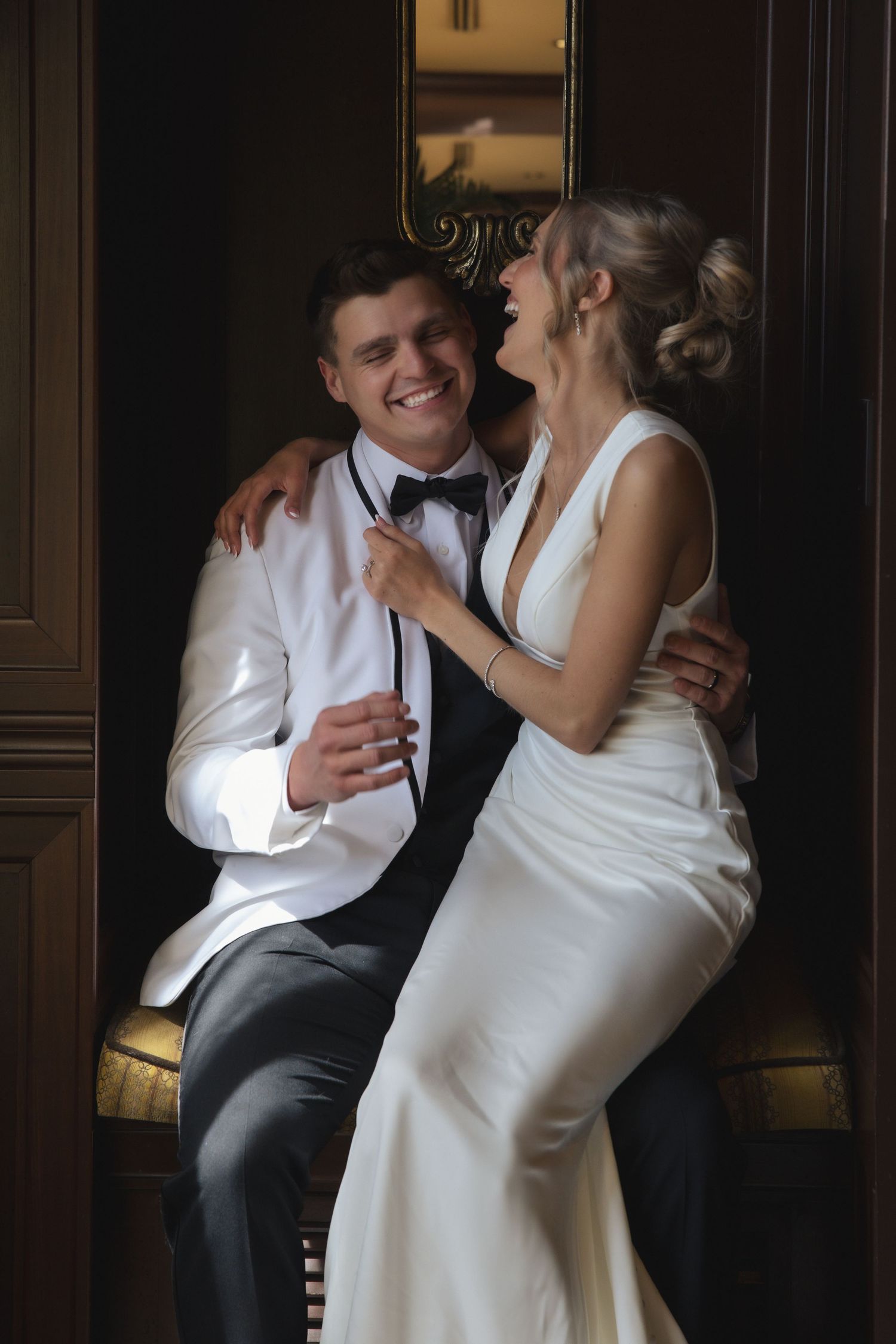 A newlywed couple sharing a tender moment together against a dark wooden wall interior.
