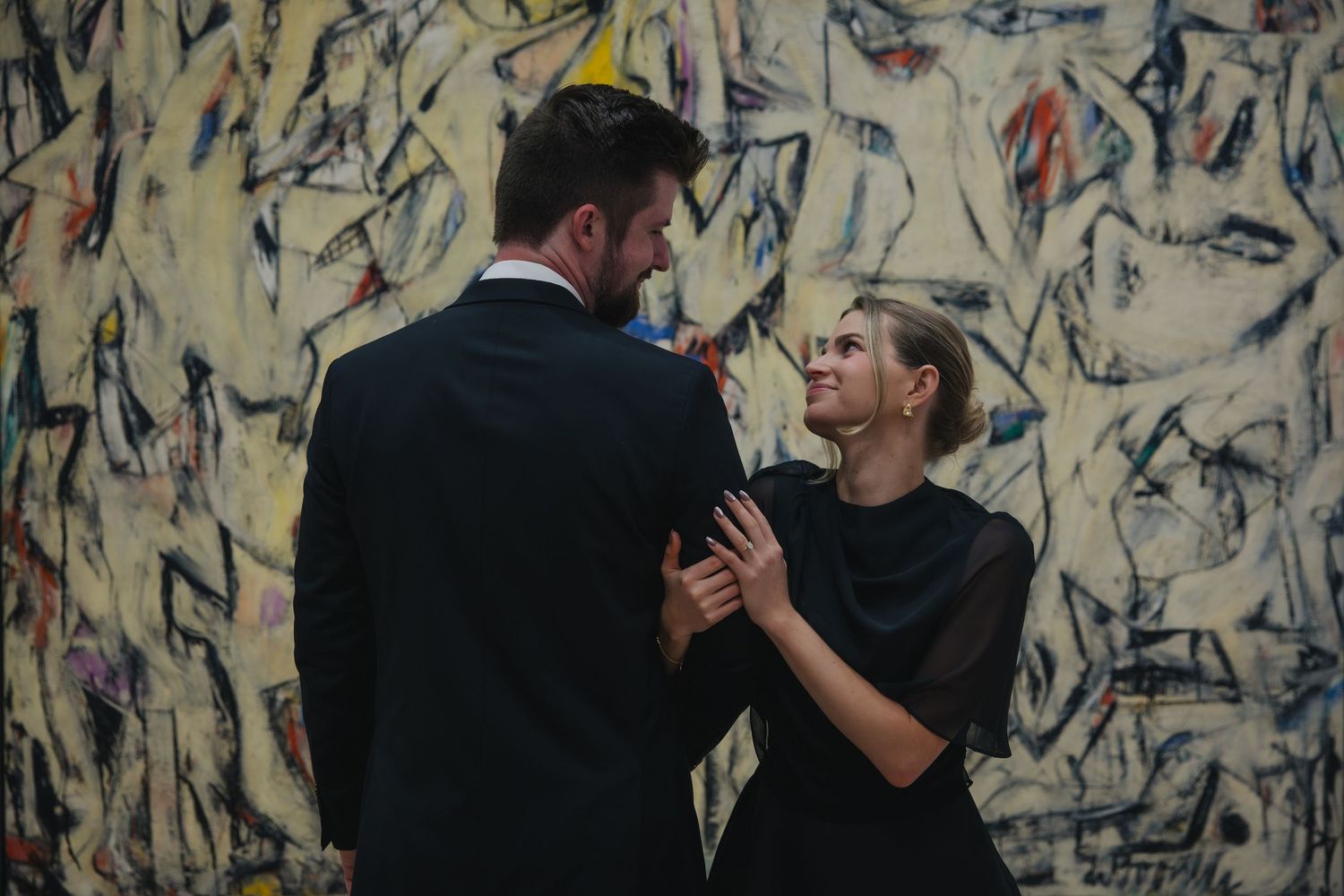 Abstract blue and white artwork forms the backdrop for performers in black formal attire during a show.