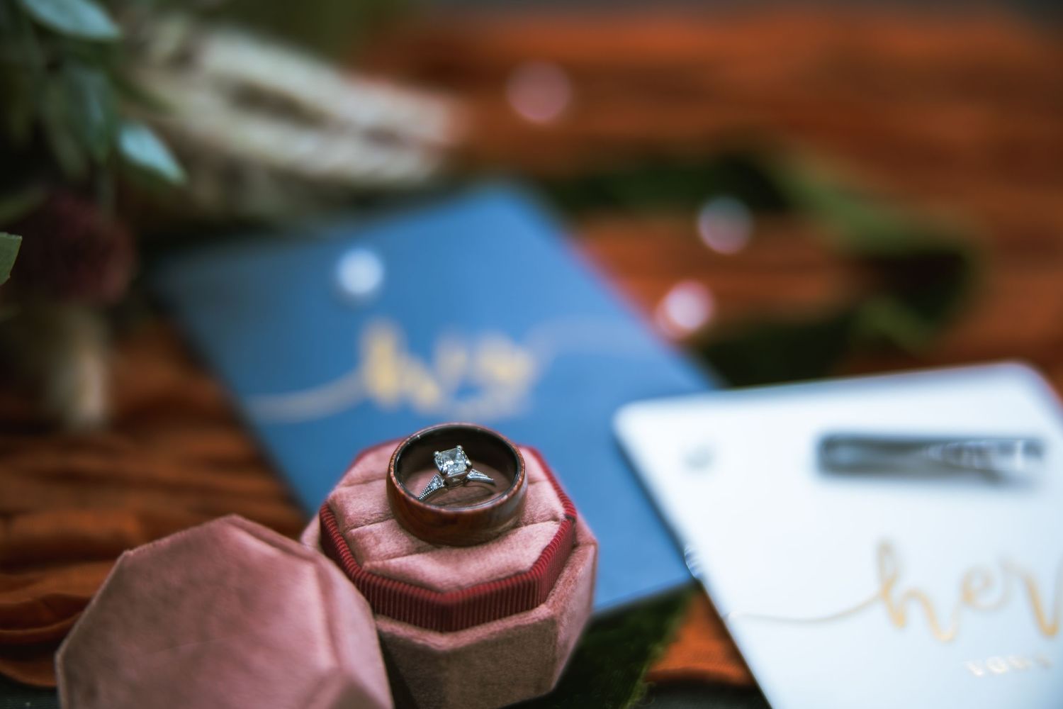 Wedding ring displayed in pink macaron with blue passport in background.