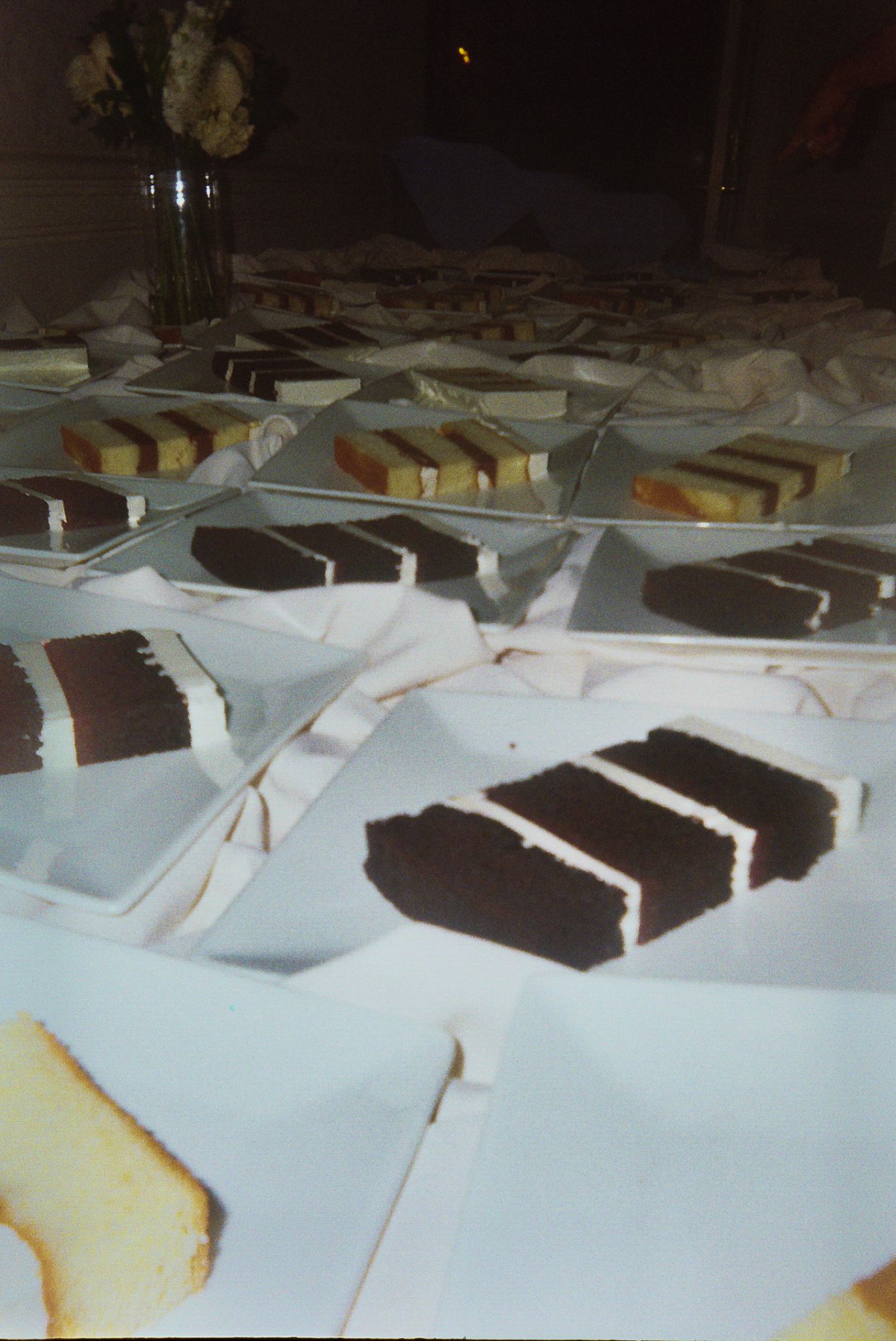 Sliced chocolate and pound cake pieces arranged on white napkins across a dark table surface.