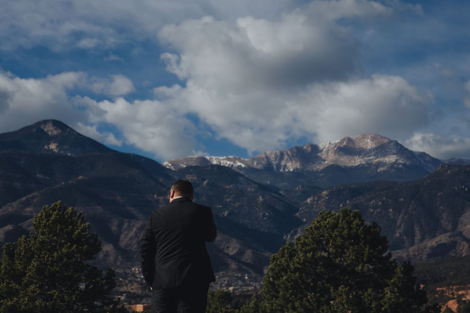 Panoramic mountain landscape with dramatic clouds over snow-capped peaks in the Dolomites during sunset.