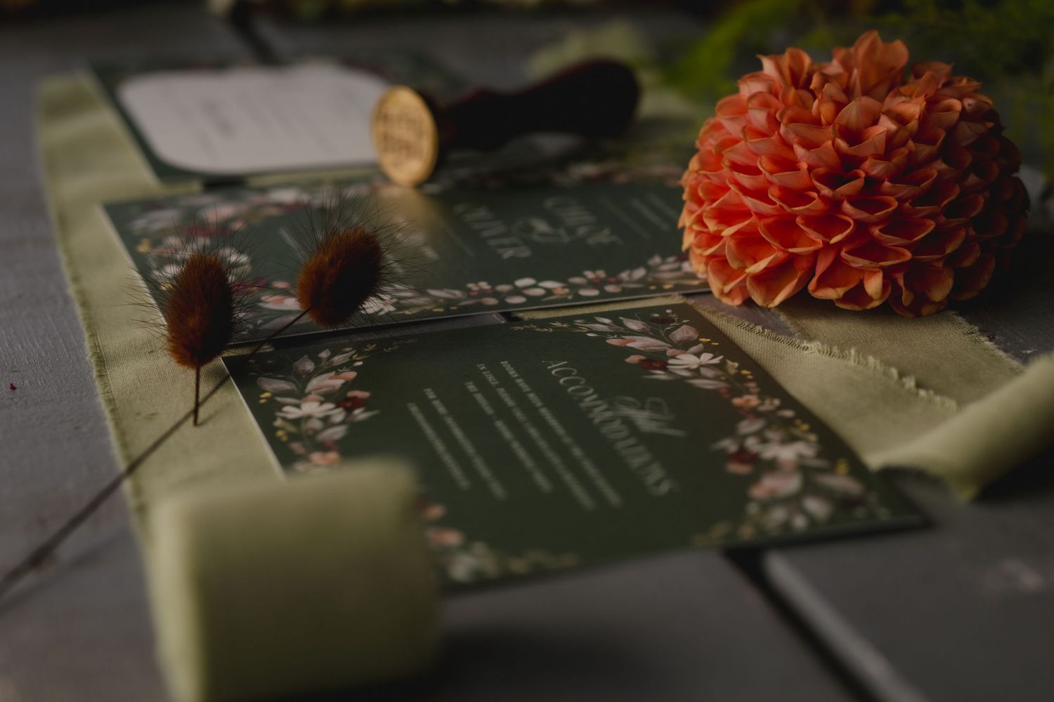 A sage green book with orange dahlia flowers and vintage decor on a dark rustic surface in moody lighting.