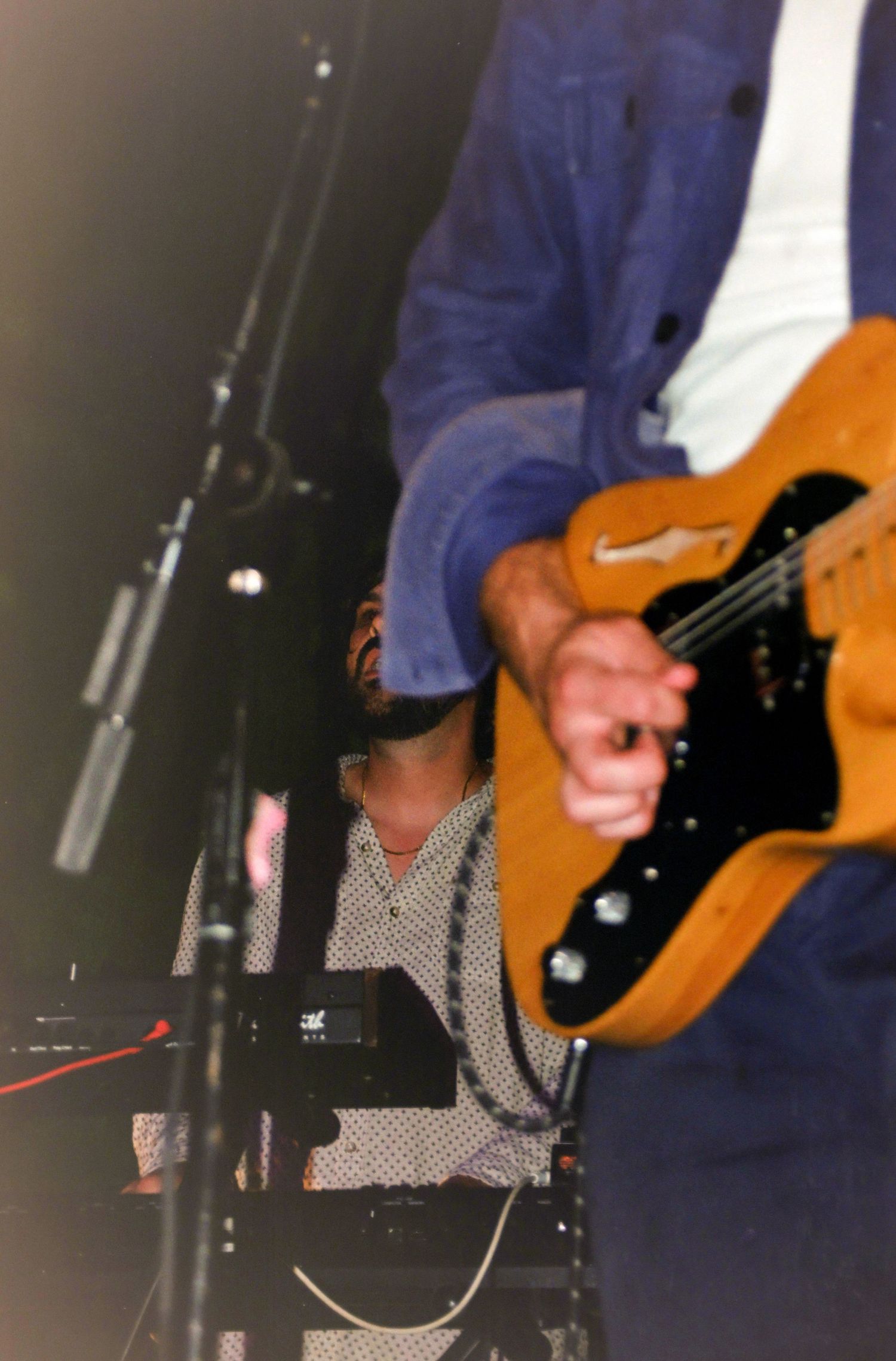 Musician playing a vintage orange Telecaster electric guitar on stage during a live performance.