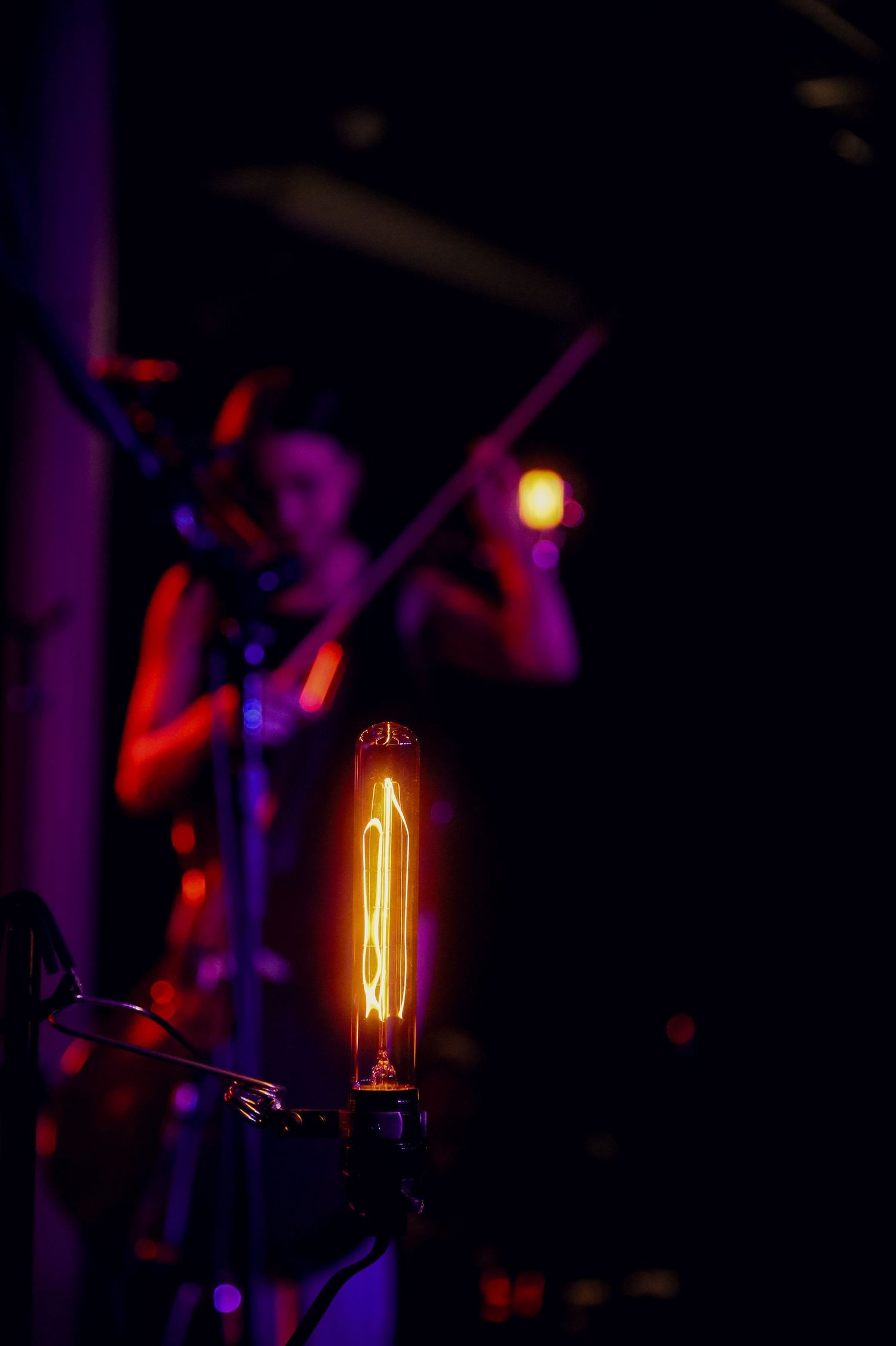 Close-up of a glowing orange light bulb filament with purple and red lighting effects in a dark setting.