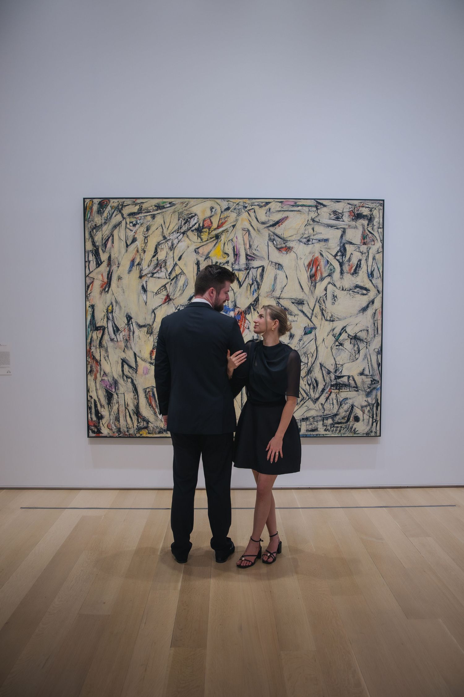 Four sequential photos of two people viewing and discussing abstract artwork in a minimalist gallery setting.