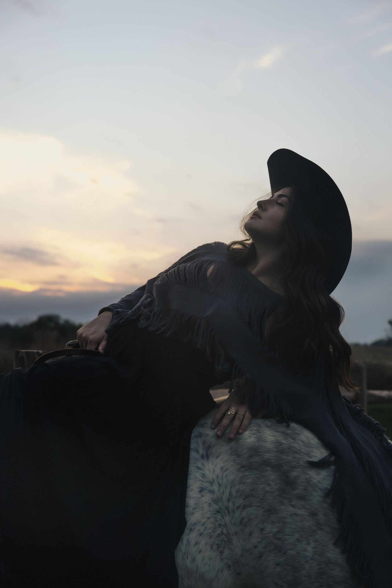 A silhouetted figure in a black hat exhales smoke against a moody sunset sky in a series of progressive shots.