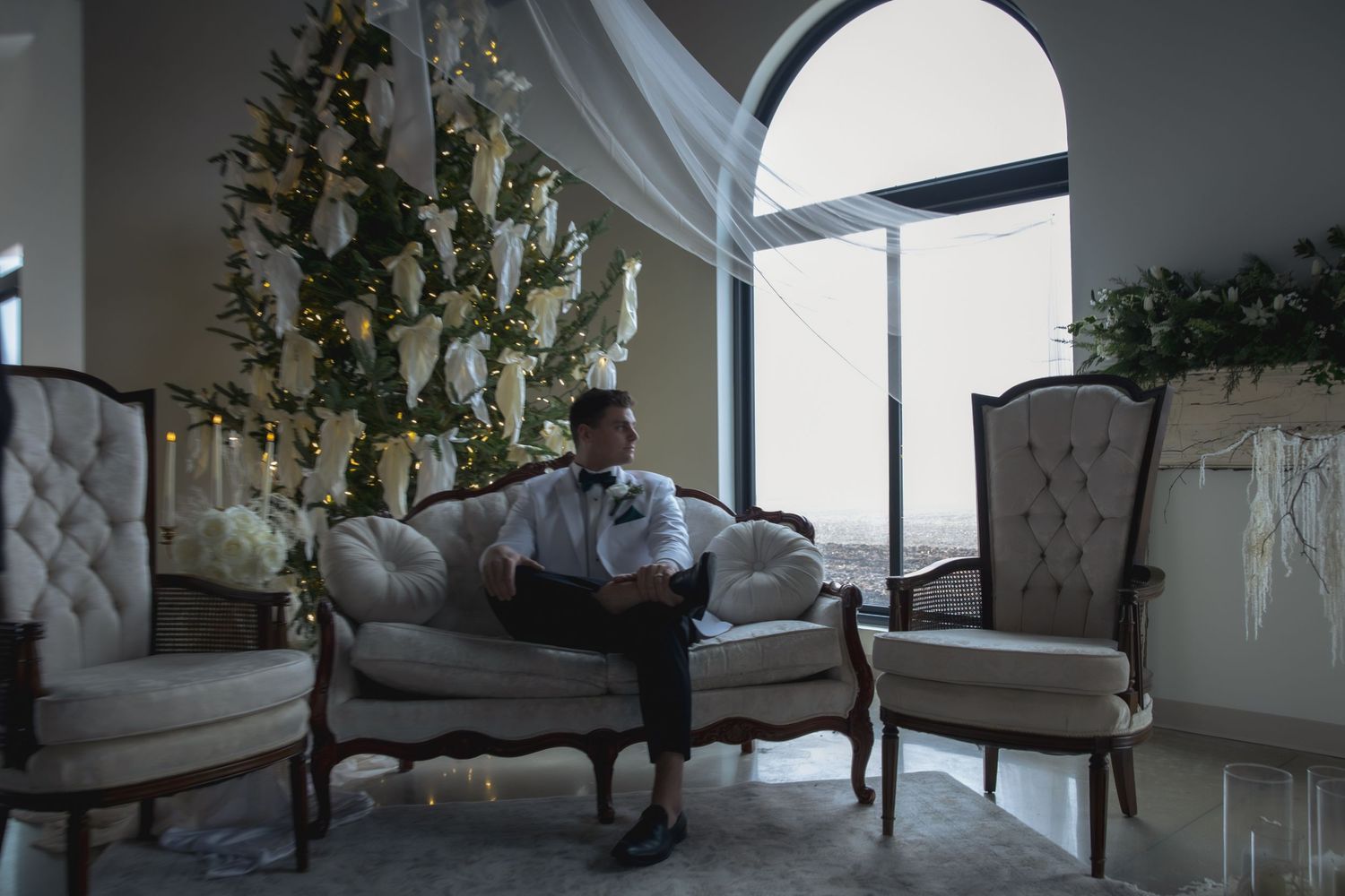 Wedding attire laid out on elegant vintage furniture in a luxurious room with floral decor.