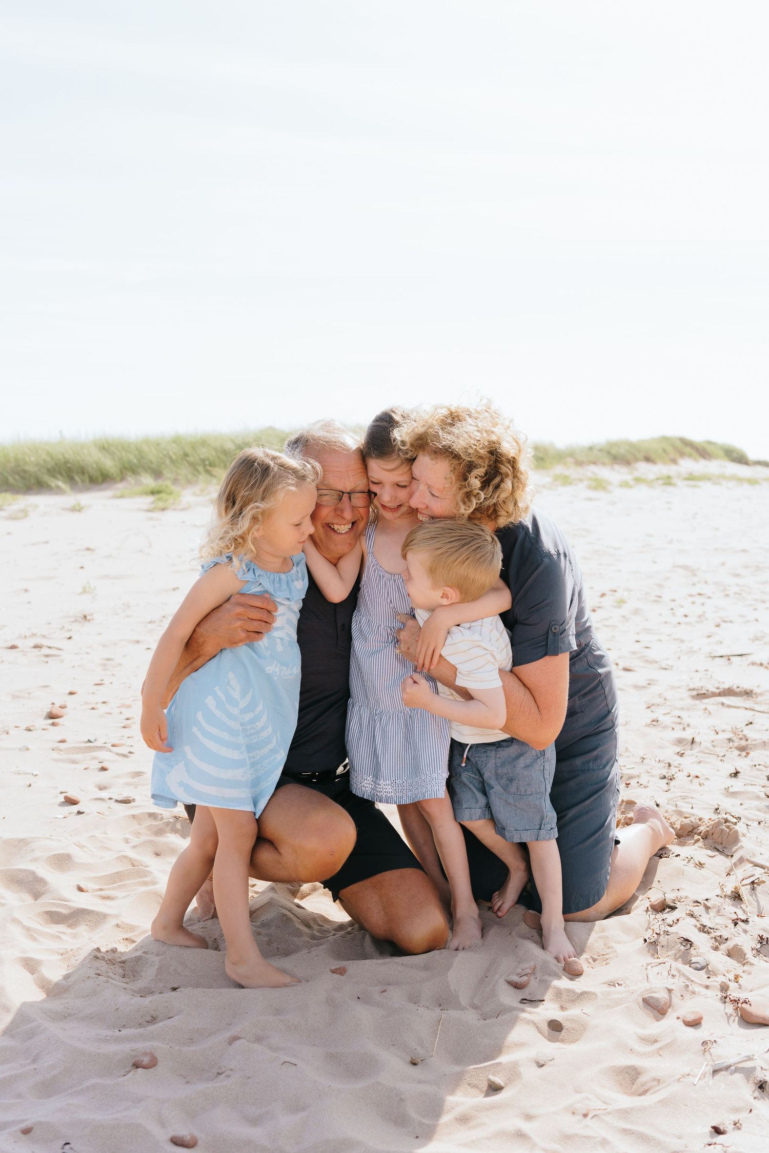 Candid family photo session showing joyful moments together on a sandy beach.
