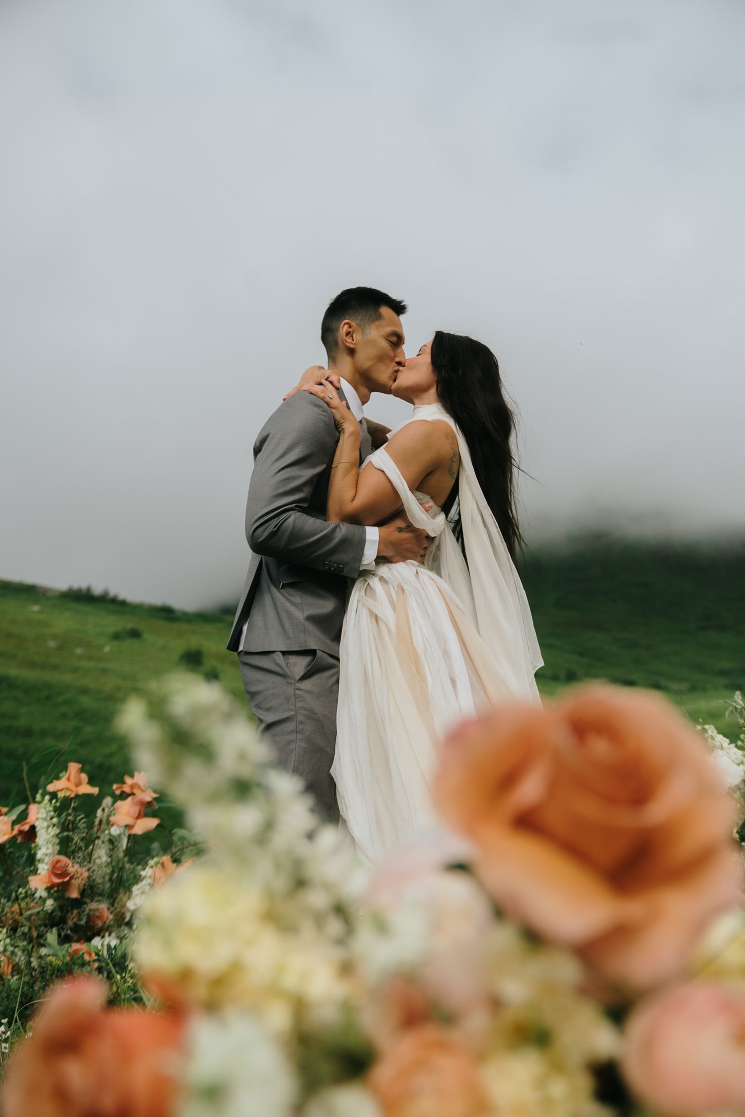 Romantic wedding moment captured with peach roses in foreground.