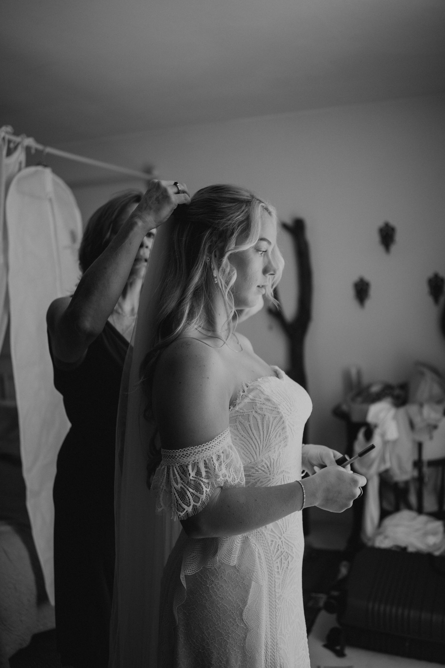 Black and white photo sequence showing a bride getting ready and putting on her wedding veil in an intimate indoor setting.