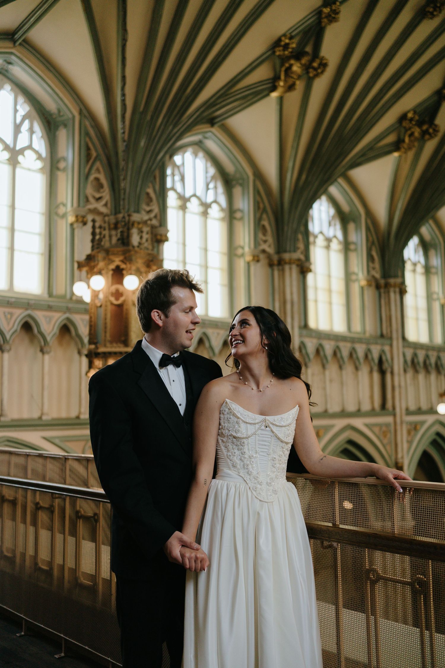 A couple shares a candid moment in a Gothic cathedral with ornate architectural details.