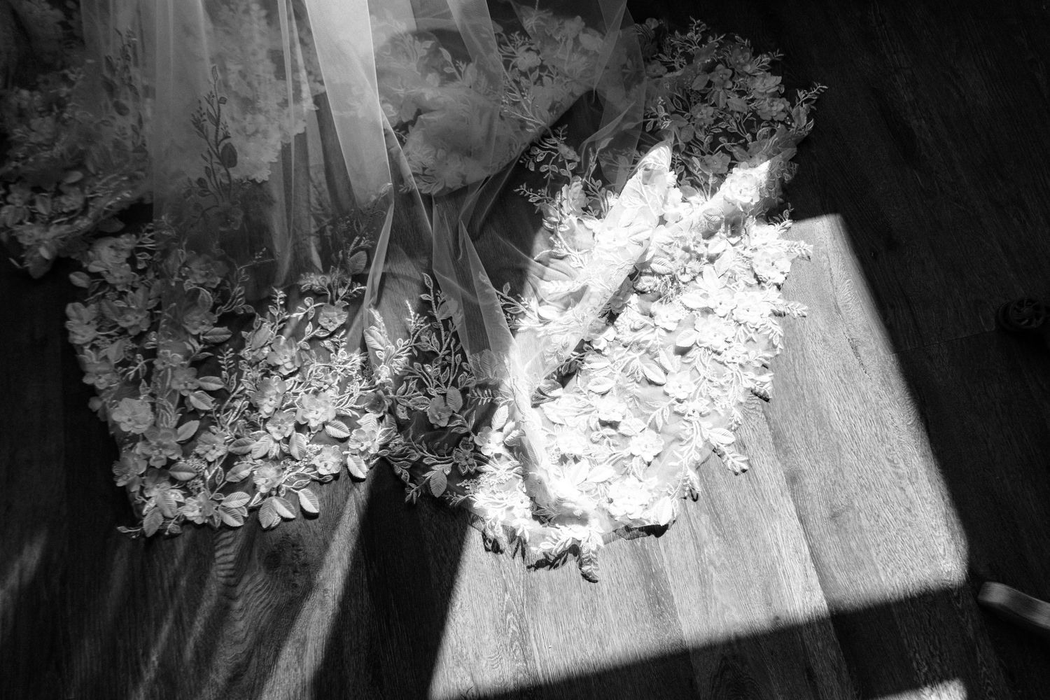 Black and white photo of dried floral wedding bouquets laying on a wooden floor with sunlight streaming through.