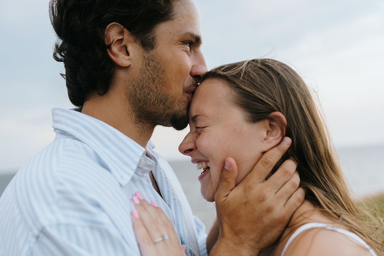 Intimate romantic moment captured between a couple against a bright sky background.