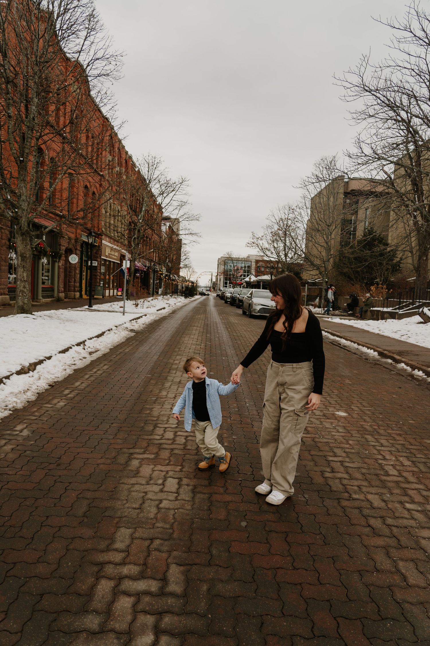 Walking together on a snowy brick street lined with historic buildings.