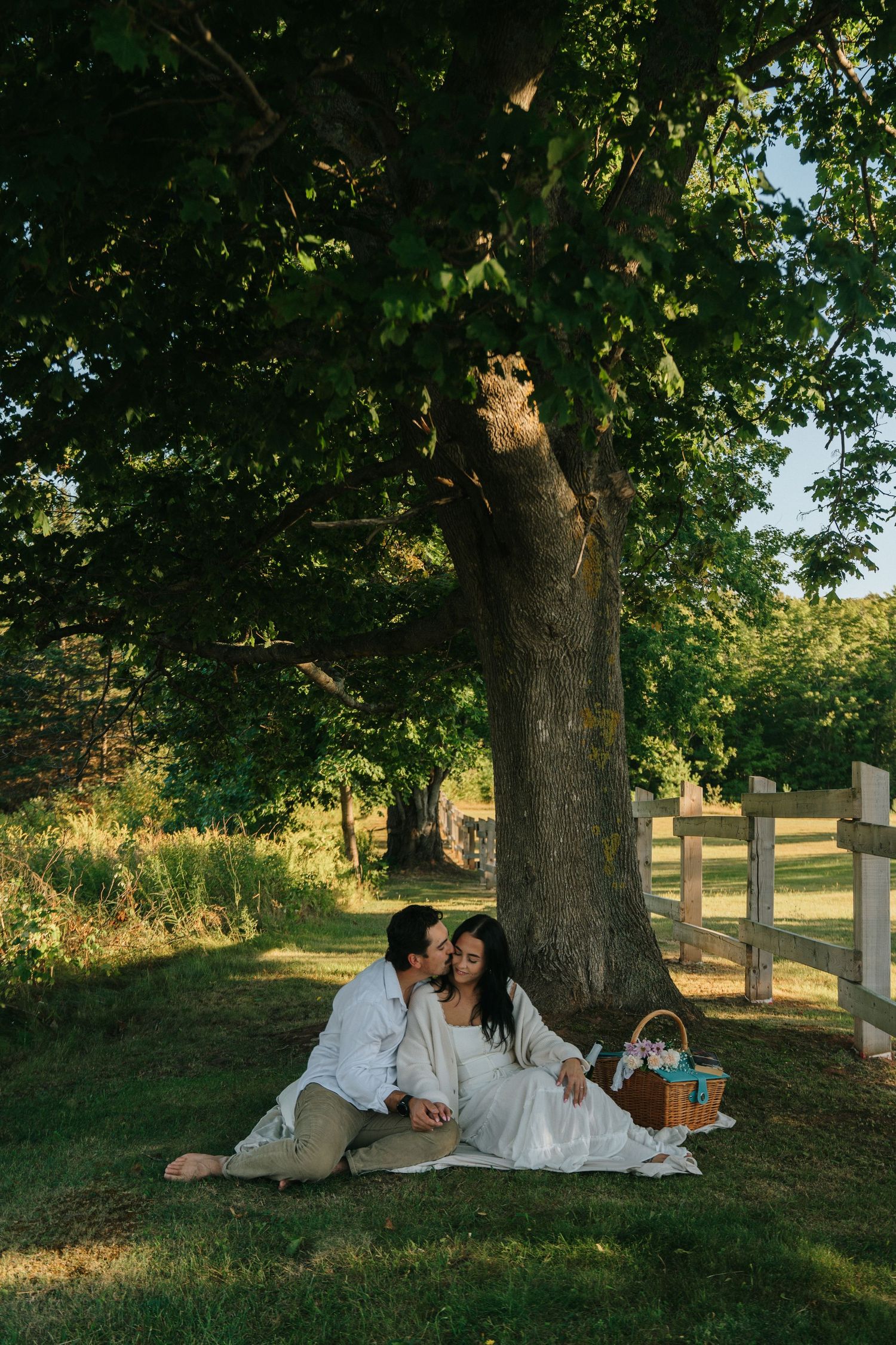 Wedding photo session under large tree during golden hour.