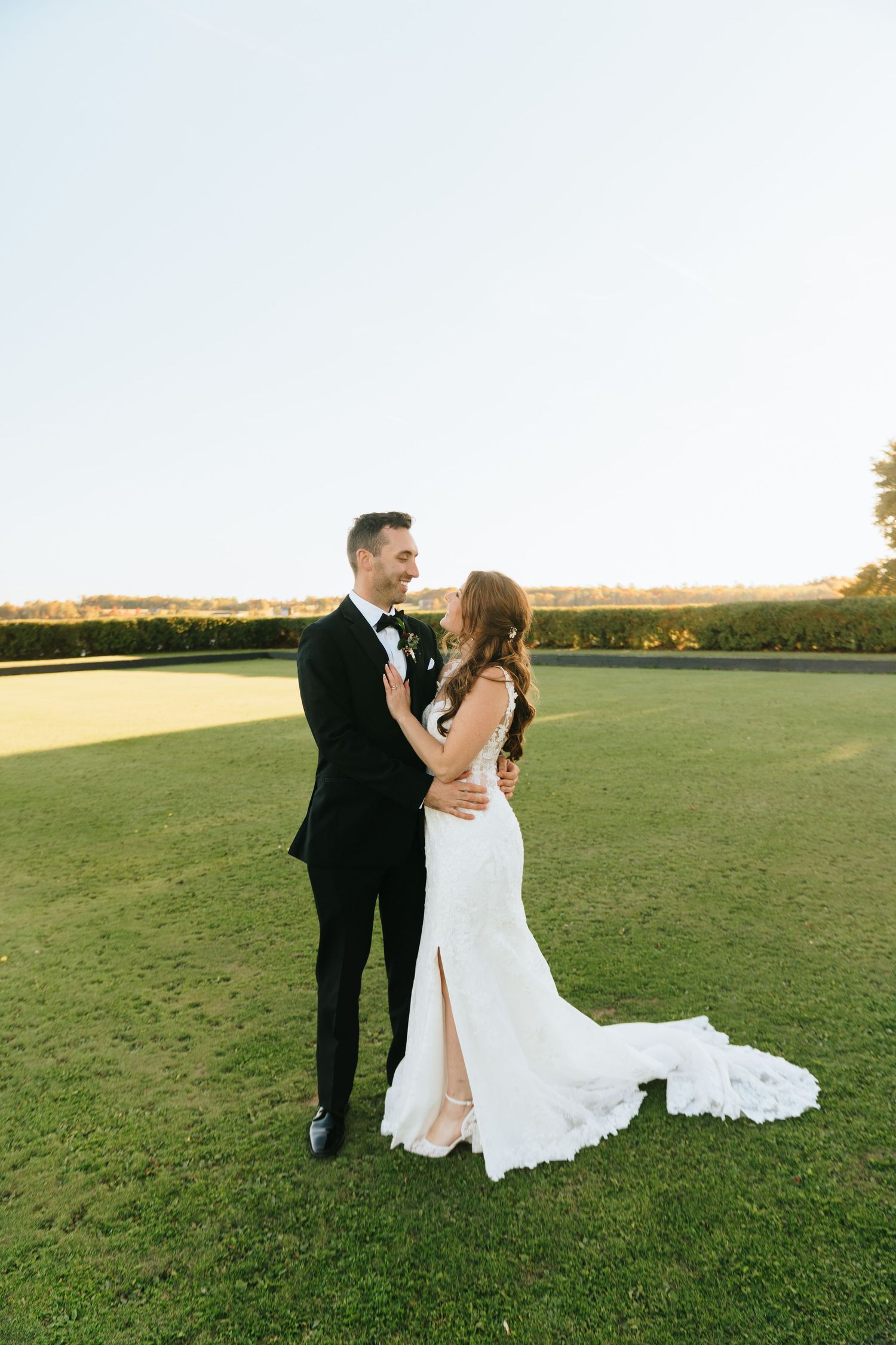 Elegant bride and groom sharing a romantic moment on lush green lawn at golden hour during their wedding.