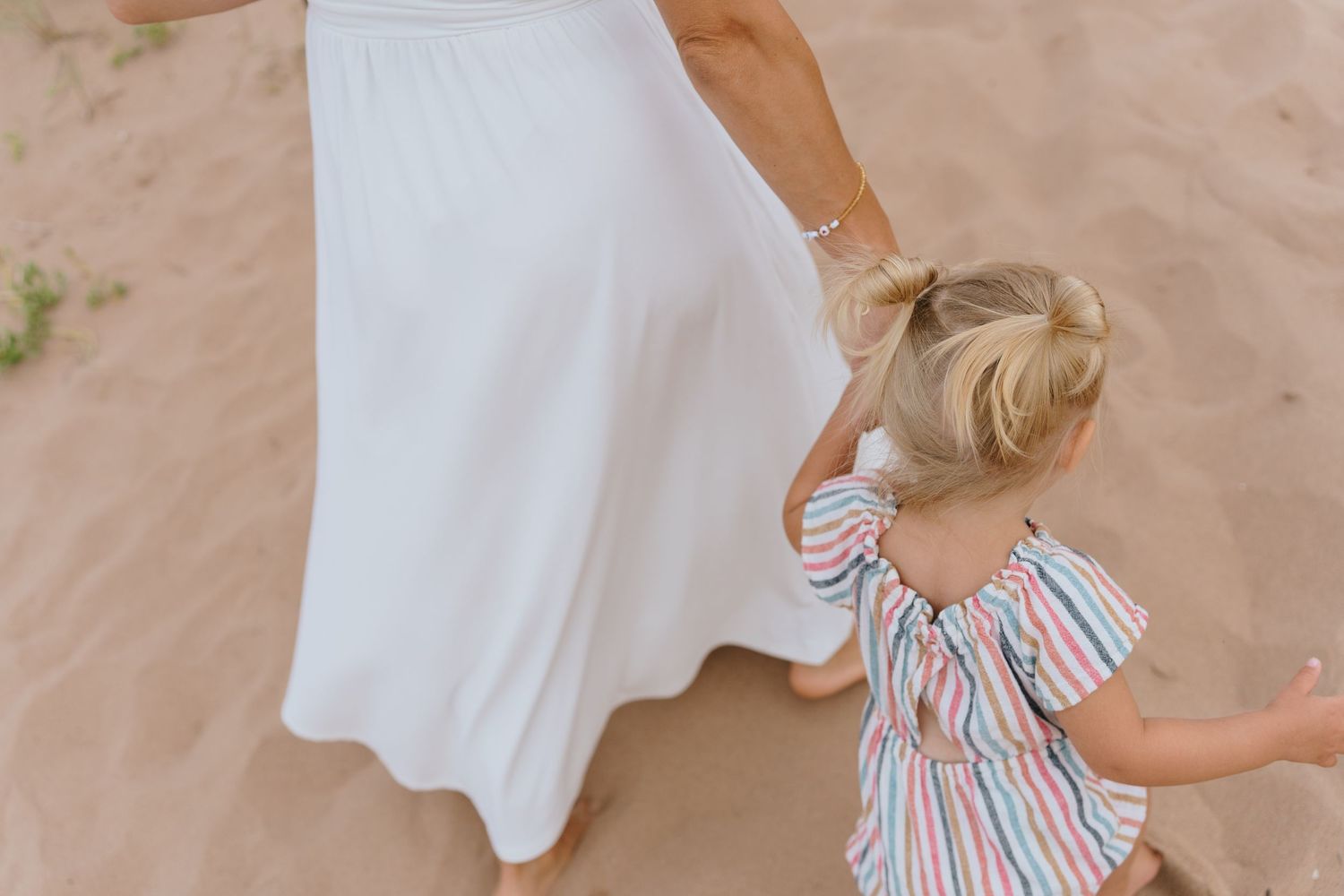 Candid beach moments with flowing white dress and striped children's clothing.