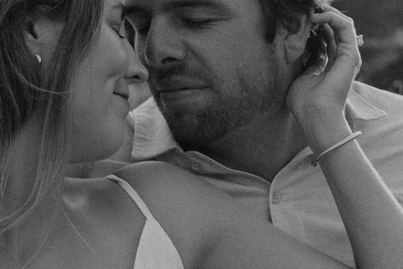 Close-up tender moment between couple in black and white photography.