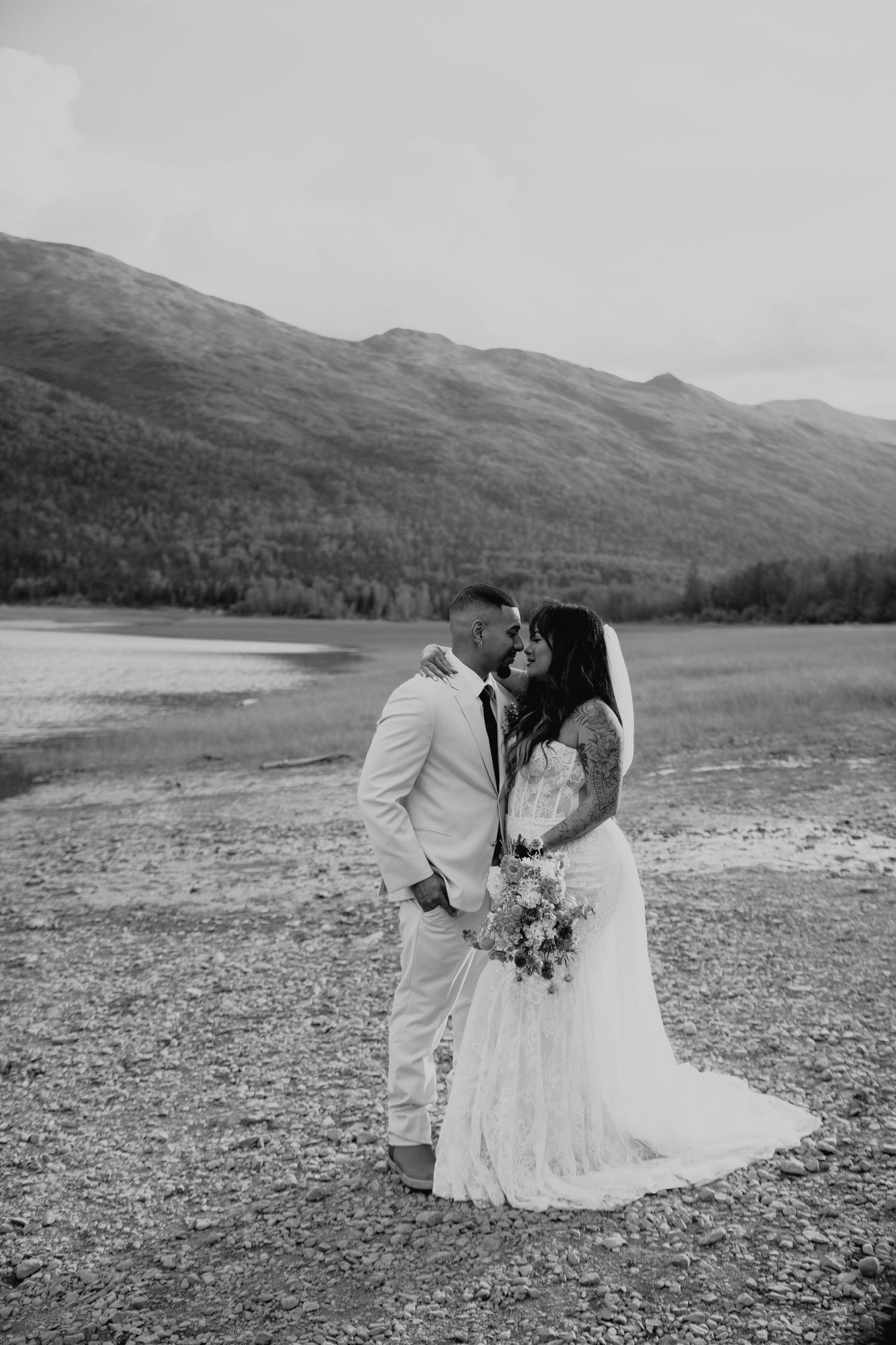 A couple shares an intimate moment by a scenic mountain at Eklutna Lake, Alaska