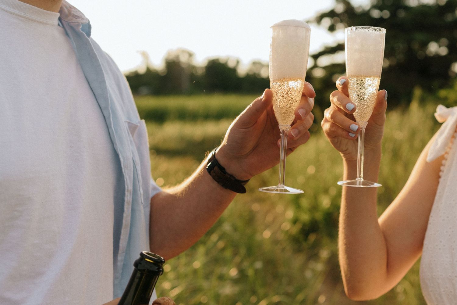 Close-up shots of hands holding glasses in a celebratory toast outdoors.