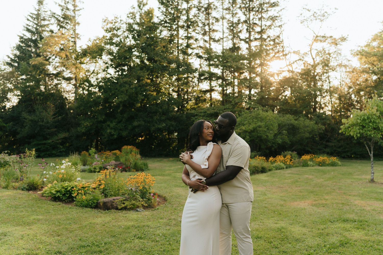 Couple sharing an intimate moment in a garden during golden hour.