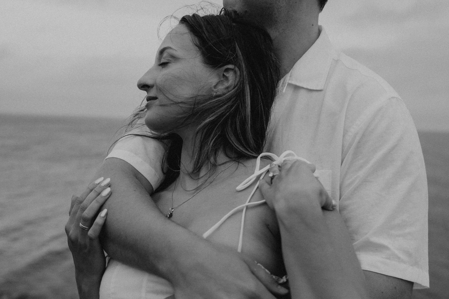 A couple embraces on a boat while enjoying a romantic moment at sea during sunset.