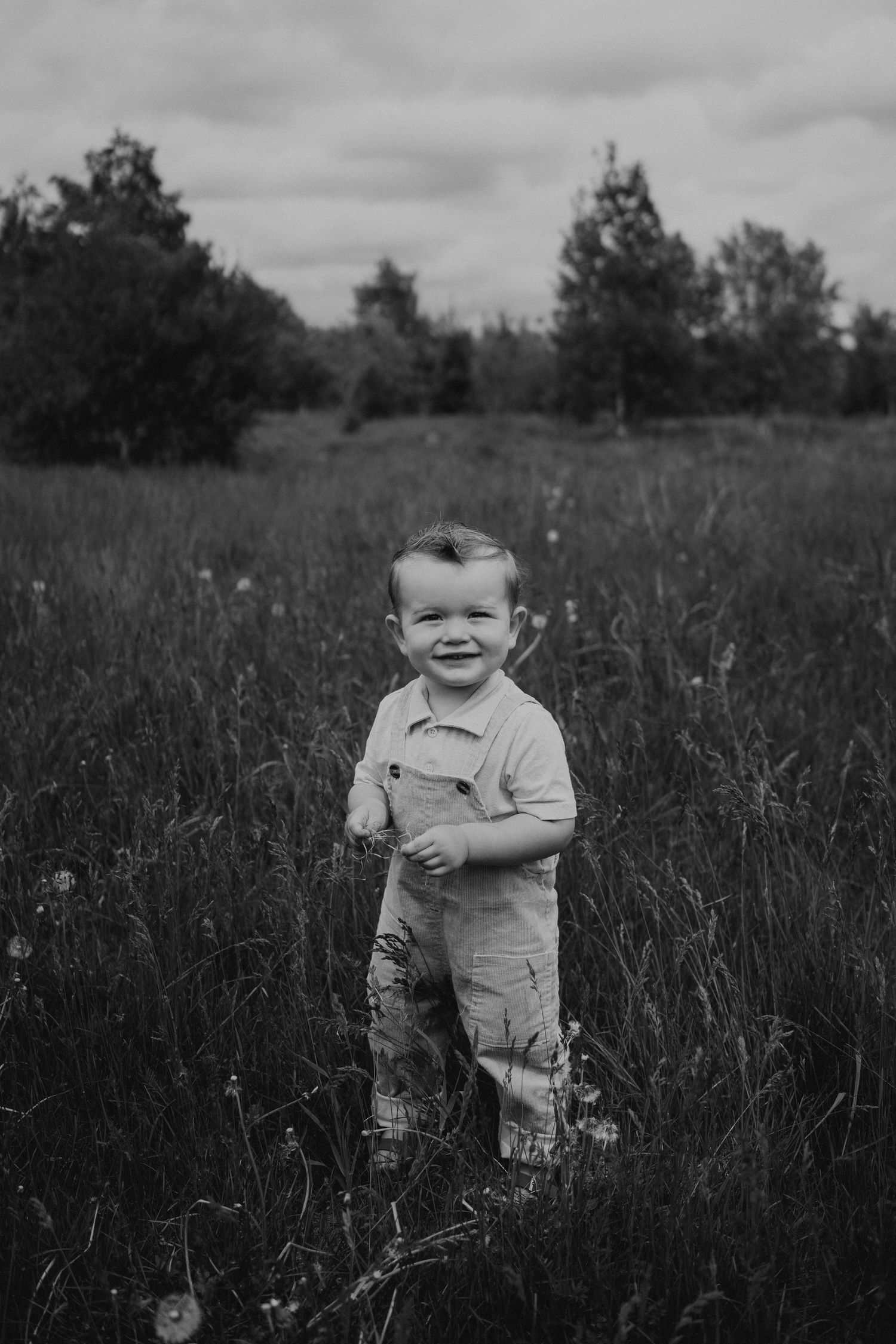 Black and white portrait series of a child playing in a wildflower field.