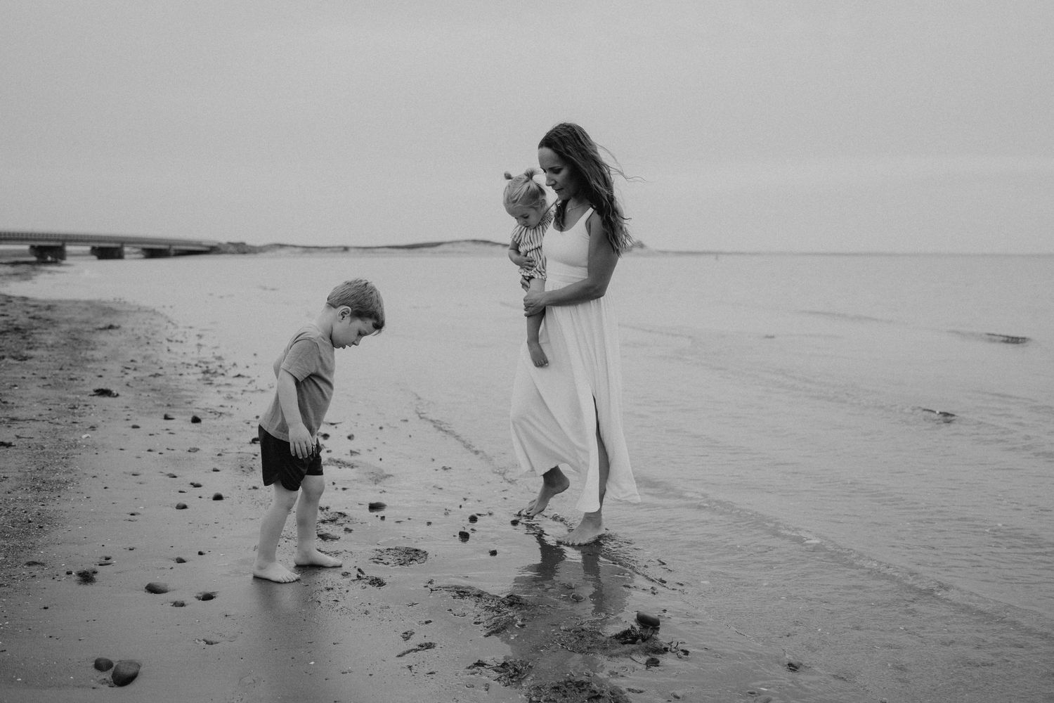 Black and white beach scene showing playful exploration at the water's edge.