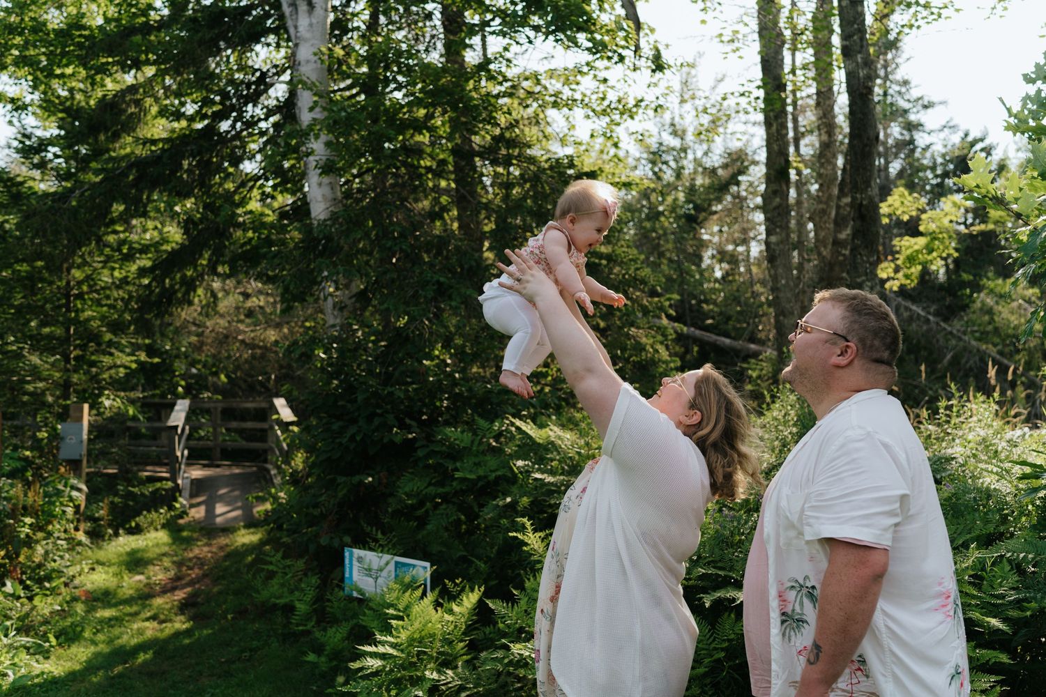 A couple shares joyful moments in a sunlit forest setting.