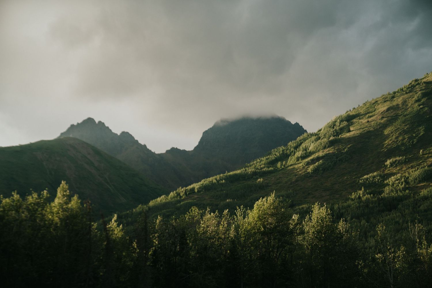 Dramatic mountain landscape with moody clouds and sunlit peaks in Alaska
