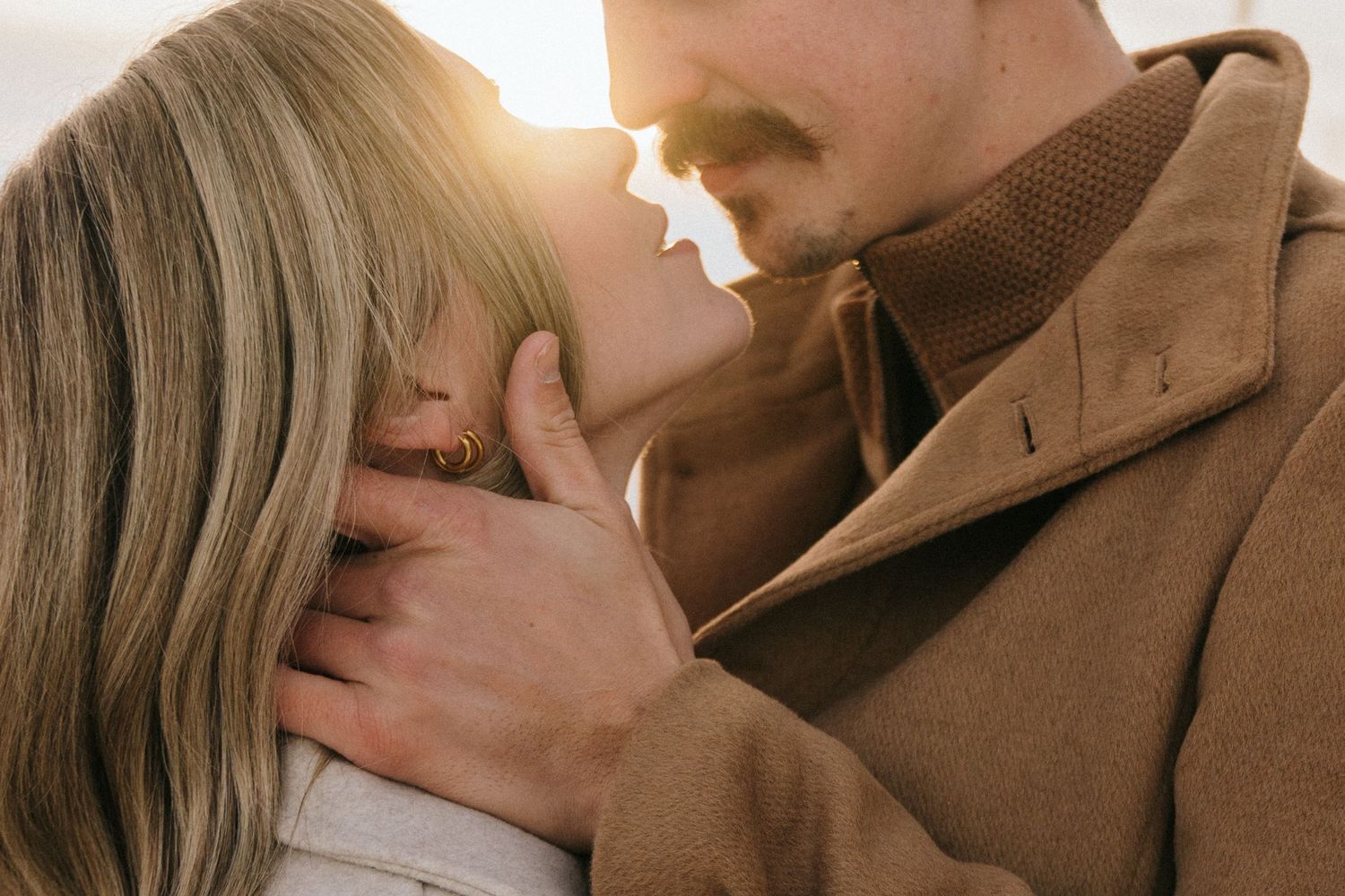Romantic couple sharing tender moments in warm earth-toned clothing.