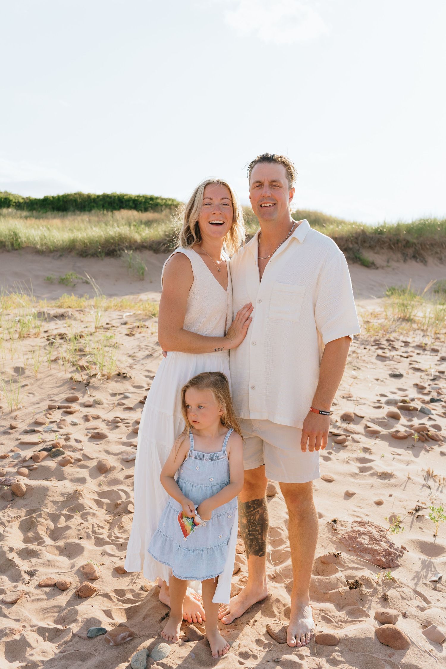 Family enjoying a sunny day together at the beach with natural sand dunes in the background.
