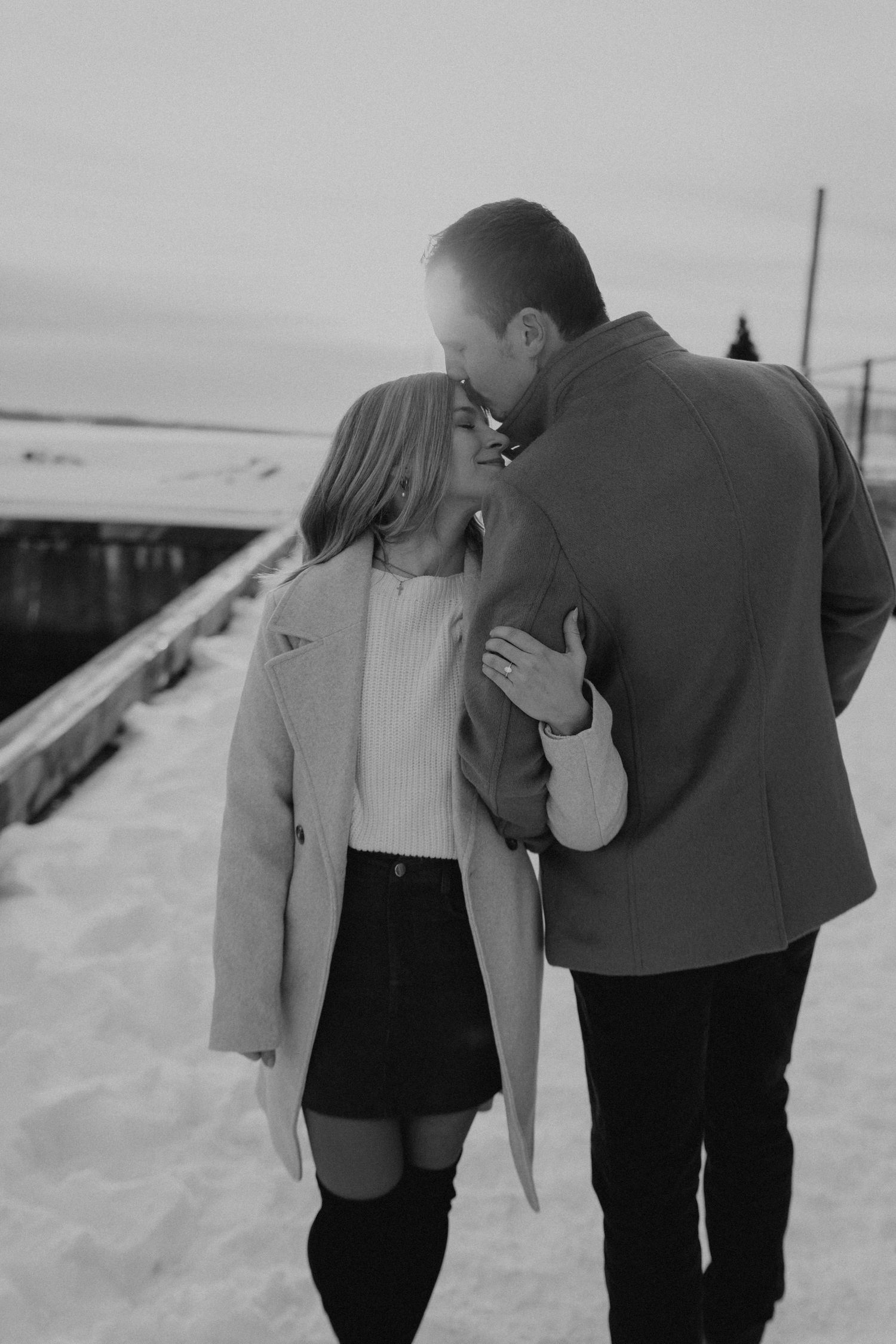 Couple in winter coats sharing intimate moments in black and white photography.