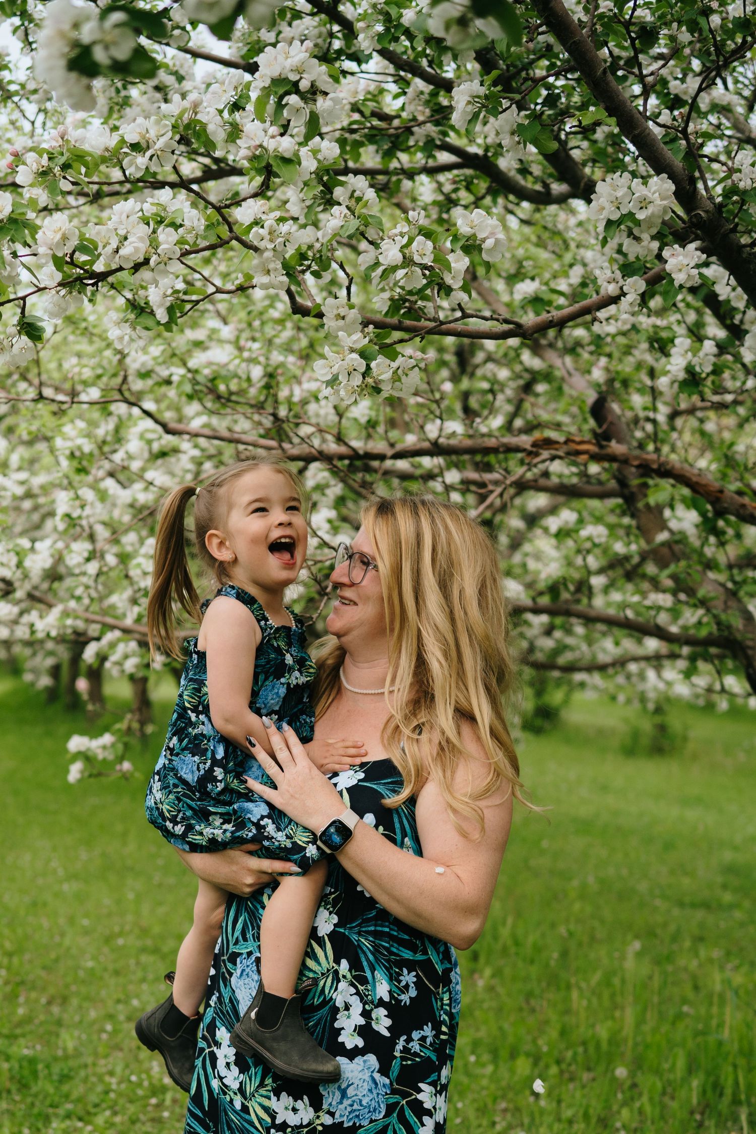 Joyful laughter under blooming white apple blossoms in springtime.