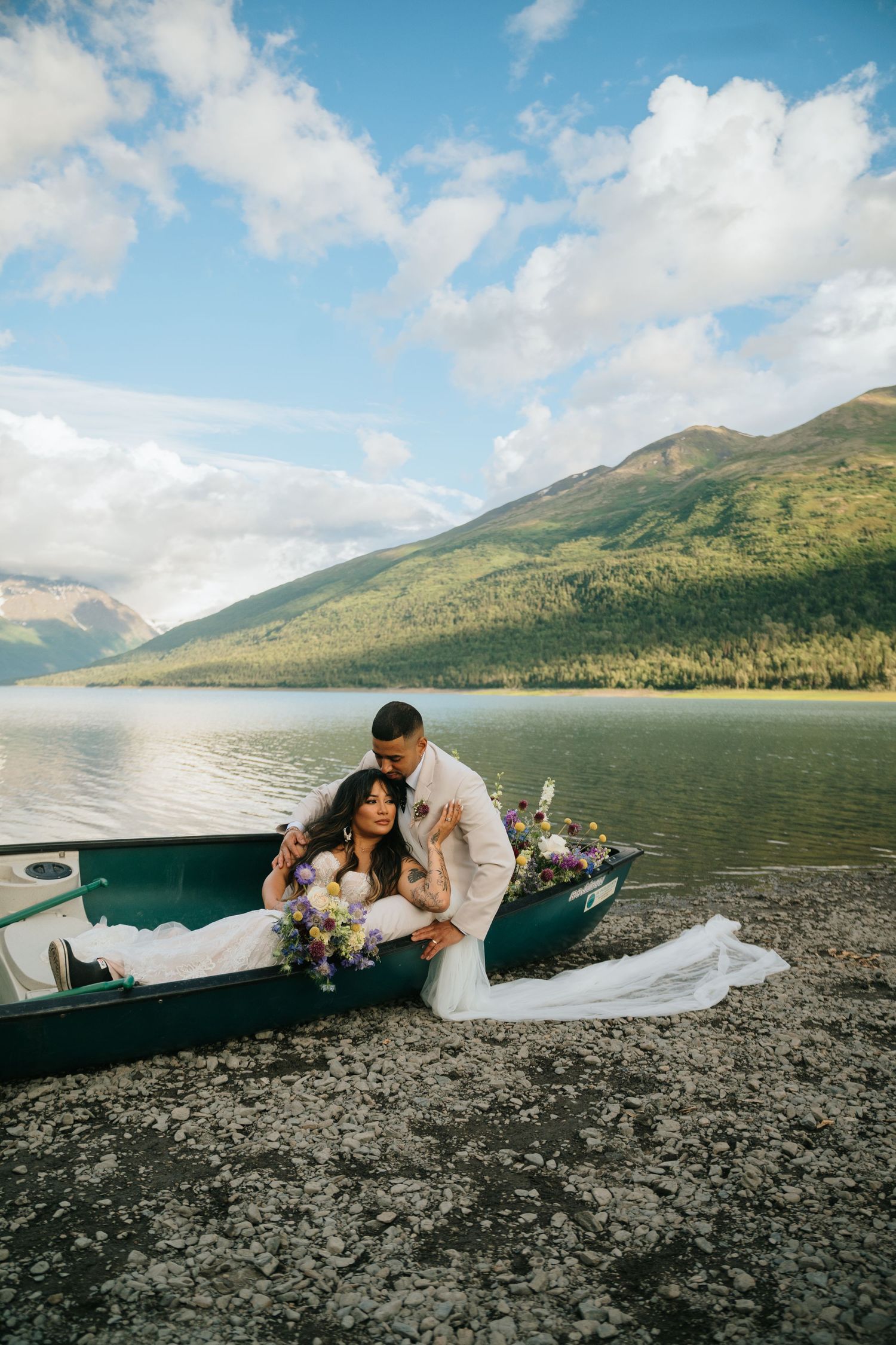 A romantic lakeside photoshoot at Eklutna Lake, Alaska with mountains and blue skies in the background.