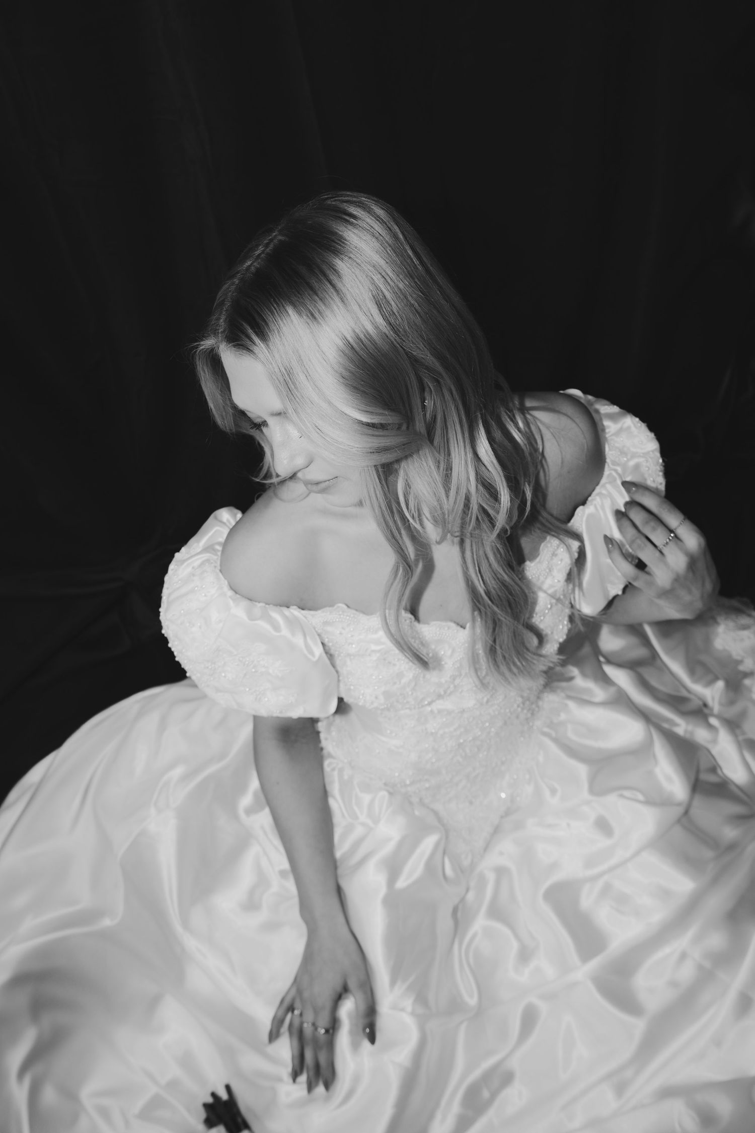 Artistic black and white portrait of flowing white wedding gown.
