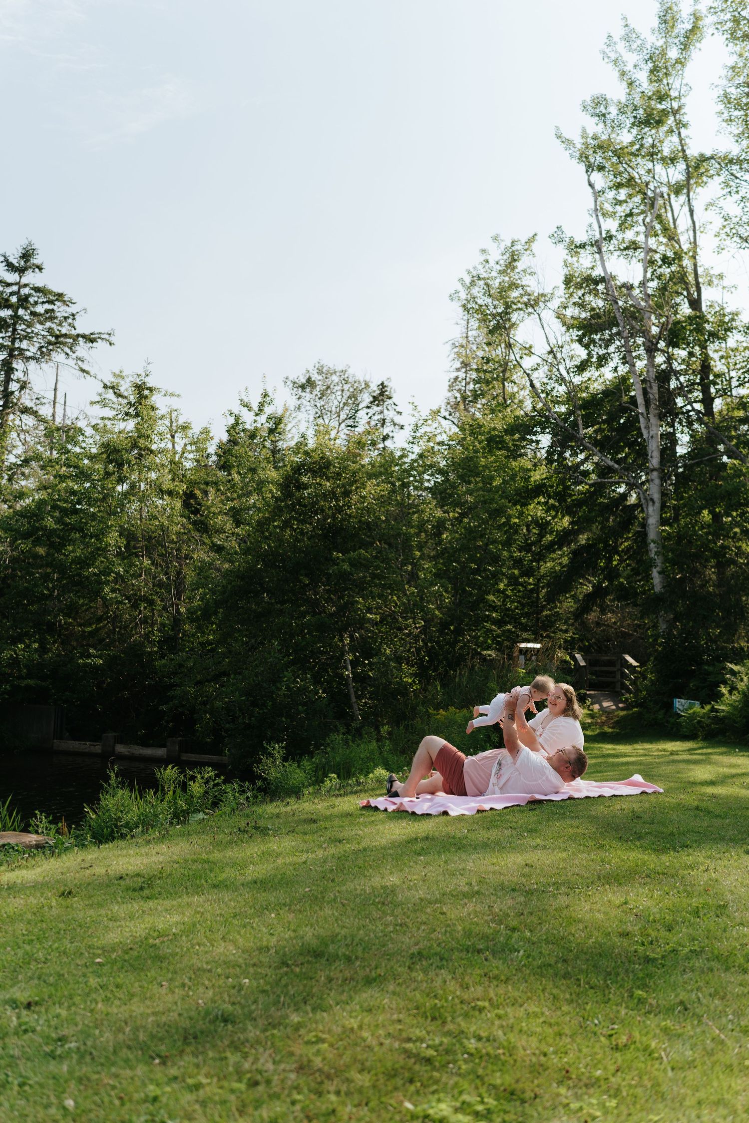 Couple relaxing on blankets in a sunny hillside meadow.