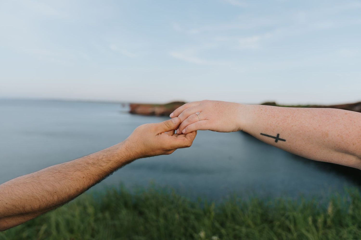 A sequence of hands reaching out to touch the horizon line where sky meets water and land.