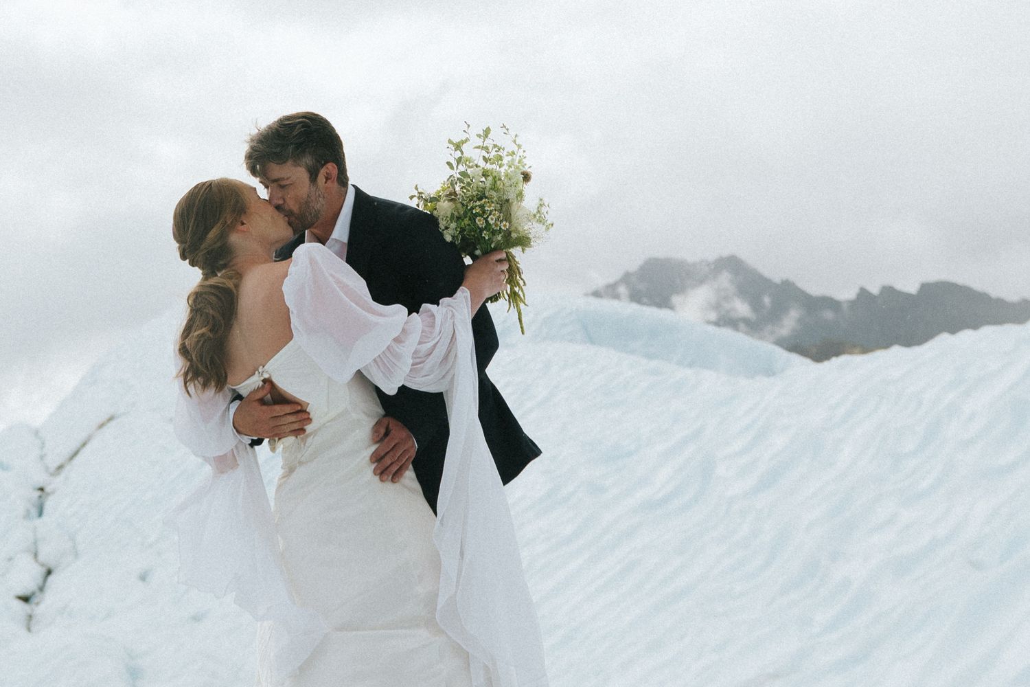 Wedding couple sharing romantic moments against snowy Alaska mountain landscape