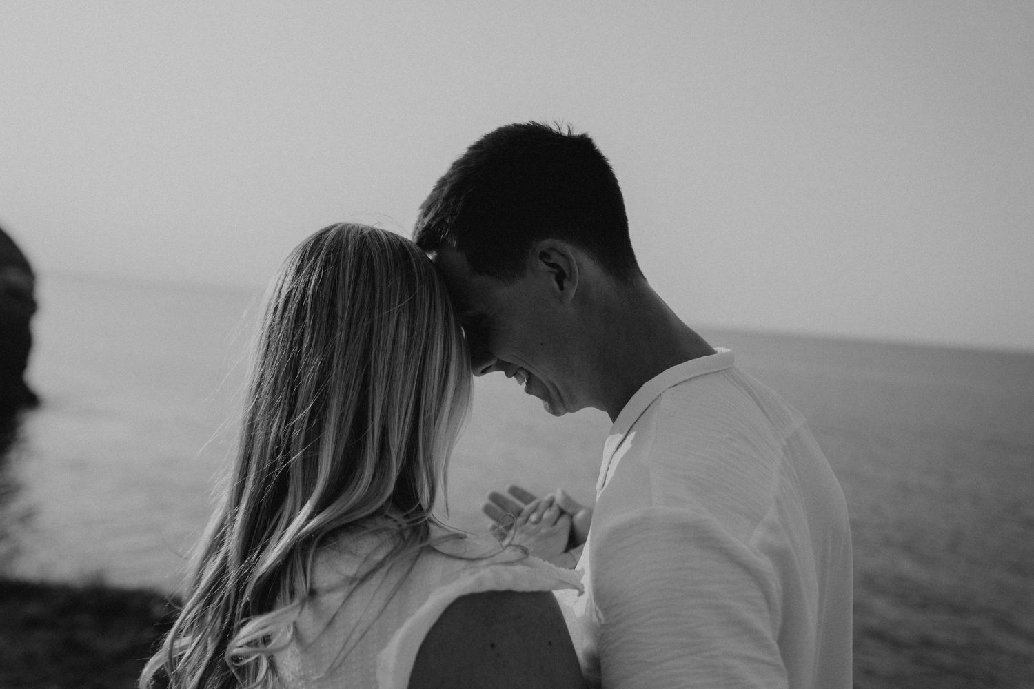 A romantic black and white photo montage shows silhouettes of a couple embracing and kissing by the ocean.