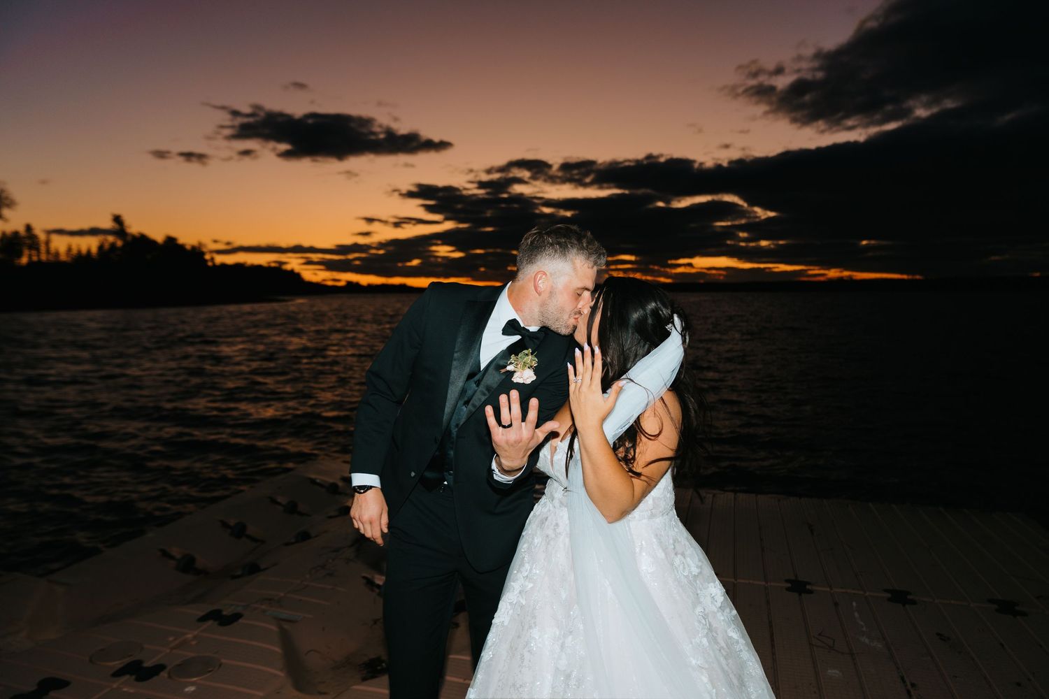 Silhouetted wedding couple shares moment on beach at sunset.