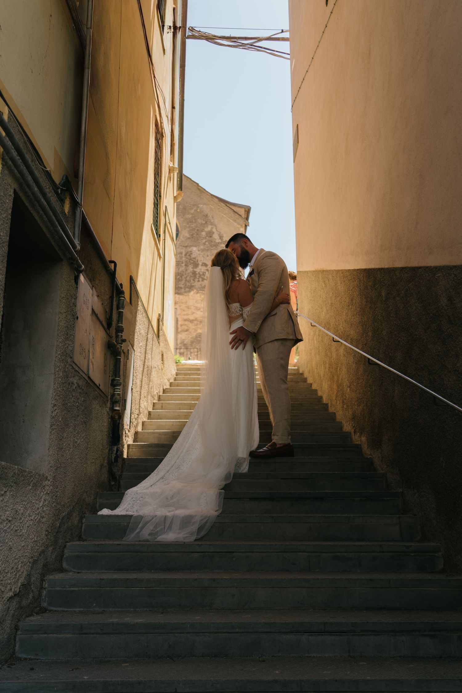 A bride in a flowing white wedding dress ascends stone steps between narrow walls in a series of artistic photos.