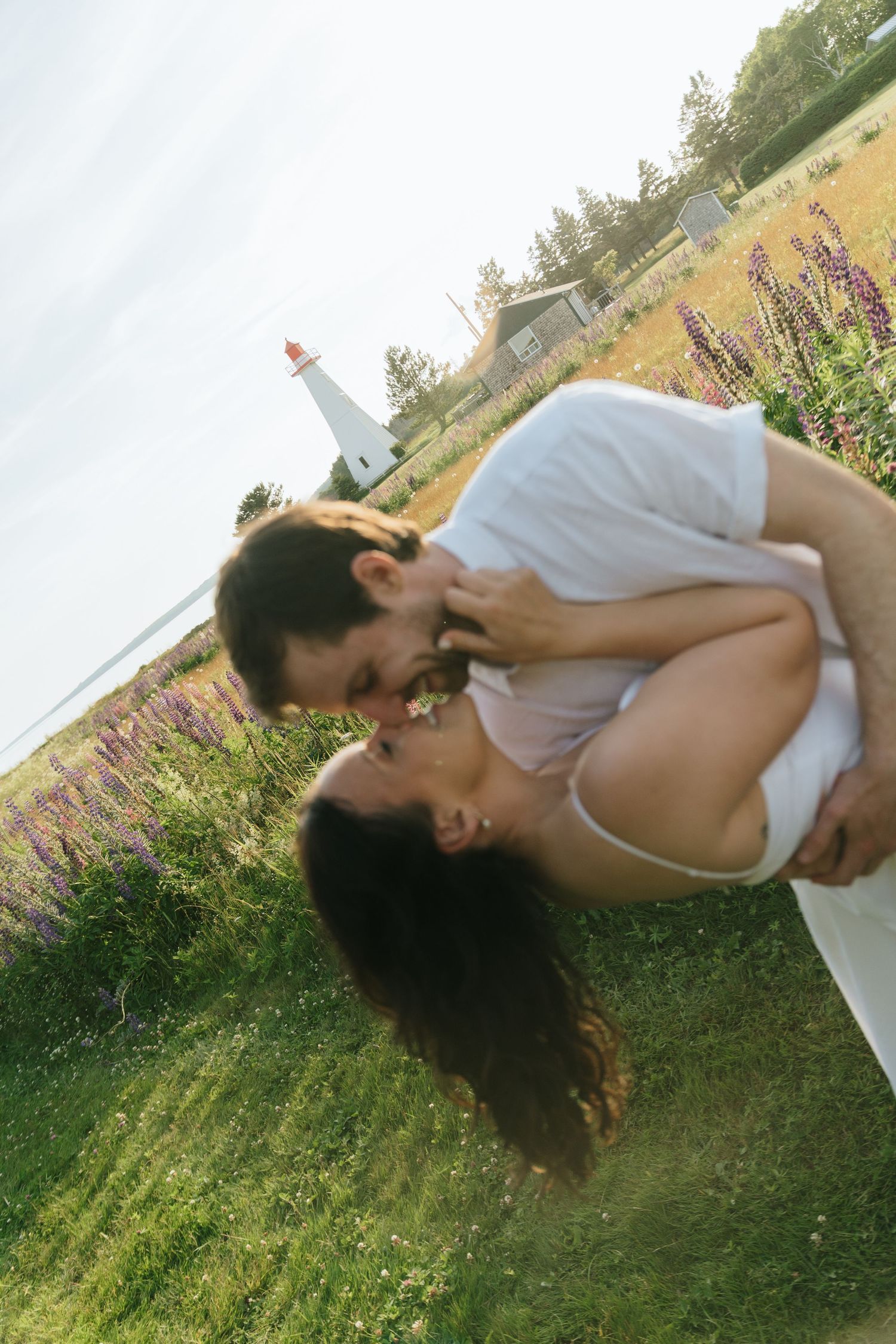 Couple embracing in a grassy field during golden hour with romantic lighting.